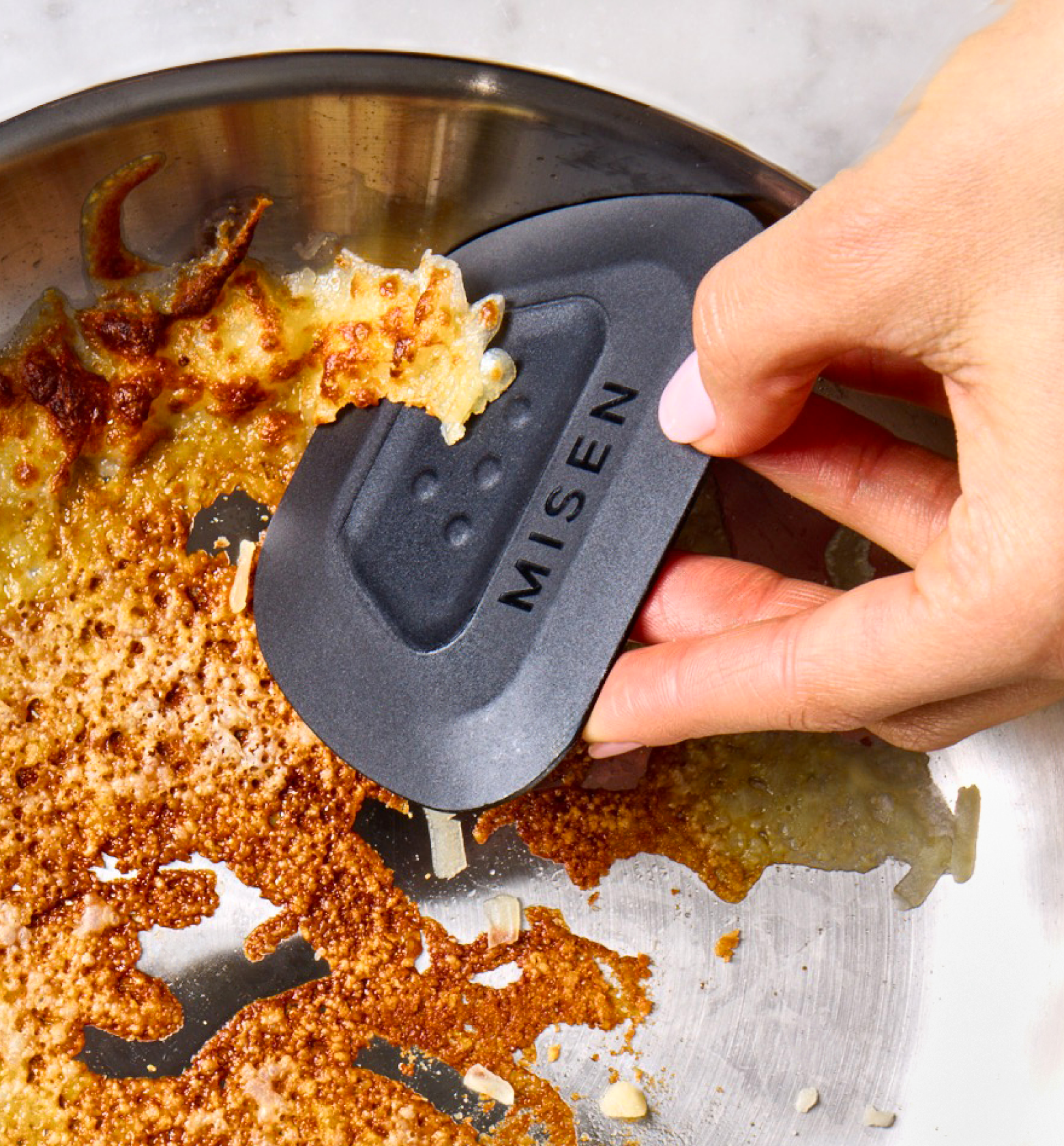 Misen pan scraper removing stuck food from stainless steel skillet